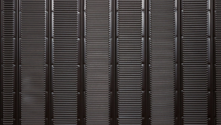 A close-up view of clean, black refrigerator condenser coils that can cause a refrigerator keep running constantly if clogged with dust.