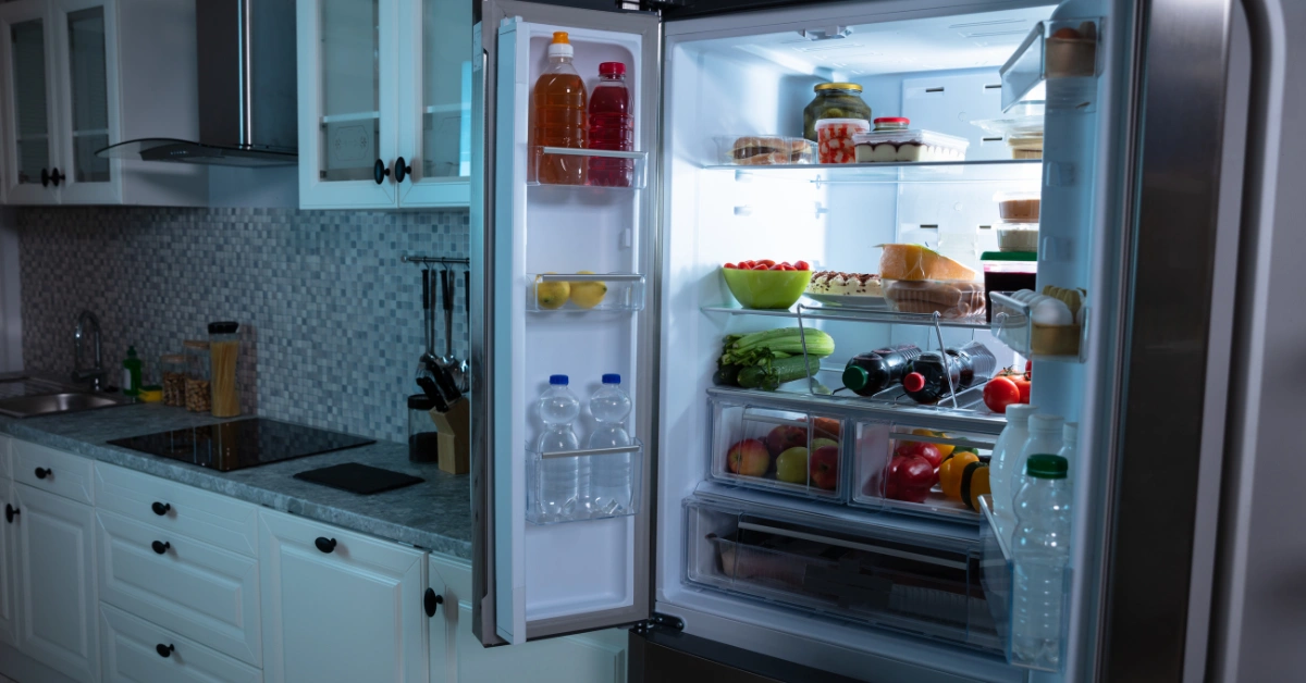 An open refrigerator full of fresh food and drinks in a modern kitchen, showing where the ice maker is located.