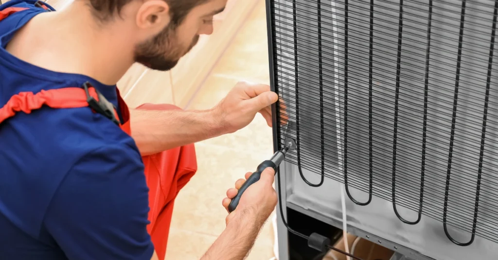A technician fixing the rear grid component of an appliance to troubleshoot why a refrigerator keep running non-stop.