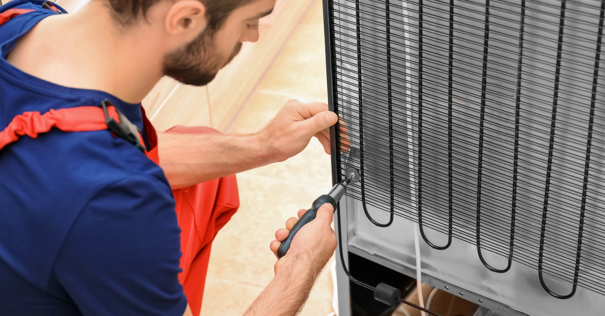 A technician fixing the rear grid component of an appliance to troubleshoot why a refrigerator keep running non-stop.